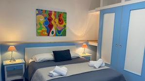 Un dormitorio con cama, dos mesitas de noche, un armario y un cuadro abstracto y colorido en la pared.