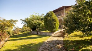 A stone pathway leading to a building with a tiled roof and a stone wall. - All Seasons Guest House (Lake Plastiras)