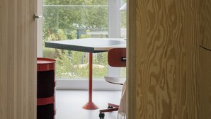 Ett rum med ett stort fönster, ett bord och en röd stol.