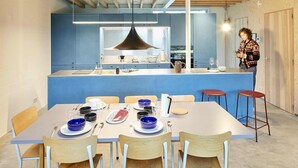 Cocina moderna con armarios azules, una isla central y un comedor con una mesa dispuesta para cuatro.