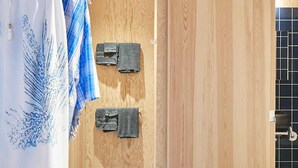 Un dormitorio moderno con paneles de madera, una cama con manta a rayas y un perchero en la pared.