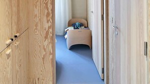 Un pasillo estrecho con paredes de madera que conduce a un dormitorio con una cama y una pequeña silla.