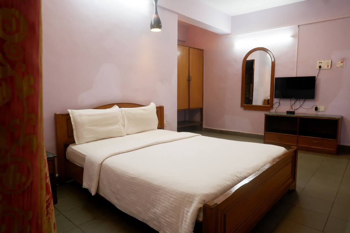 A neatly arranged bedroom with a bed, a television, and a wardrobe.