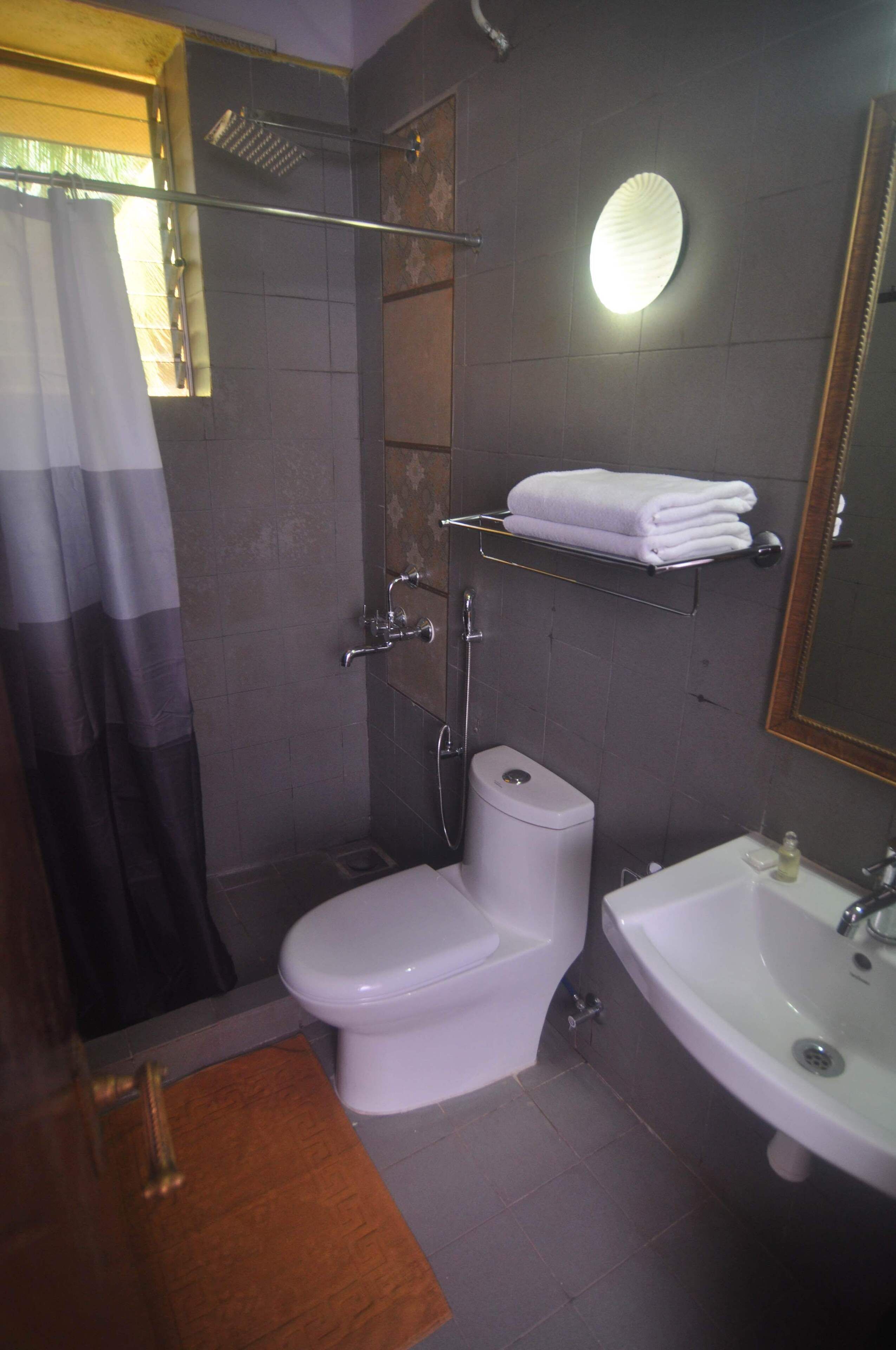 Ein Badezimmer mit Toilette, Waschbecken, Dusche und Handtuchhalter.