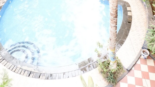 A swimming pool surrounded by palm trees and a checkered floor. - Falcon Resorts by Dia Hotels (Calangute)