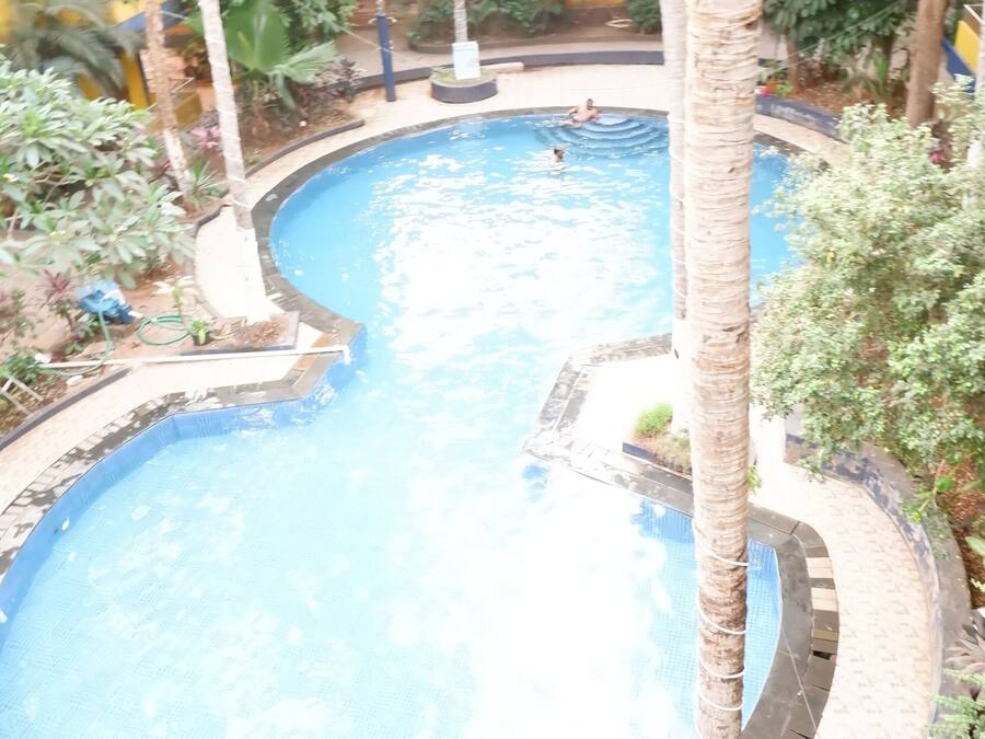 Uma piscina rodeada por palmeiras e um chão xadrez.