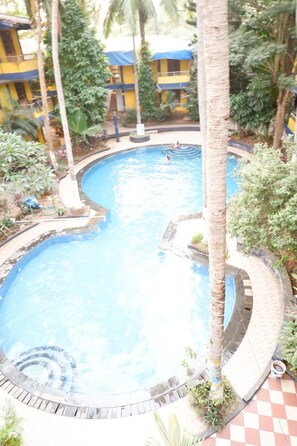 Ein Swimmingpool, umgeben von Palmen und einem Schachbrettmuster-Boden.