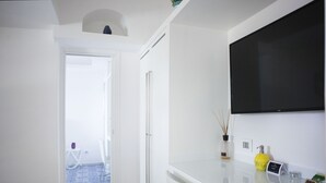 Habitación de hotel moderna con un televisor de pantalla plana grande montado en la pared, un mostrador de recepción blanco y un suelo azul con estampado.