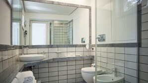 Un baño moderno con un espejo grande, un lavamanos, un inodoro y un bidé.