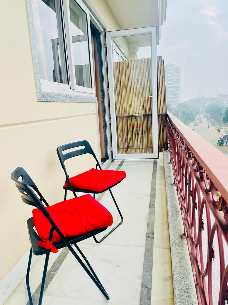 A balcony with two chairs, a wooden fence, and a view of the city.