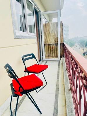 A balcony with two chairs, a wooden fence, and a view of the city. - Zen Suites - Golf Course Road (Gurugram)