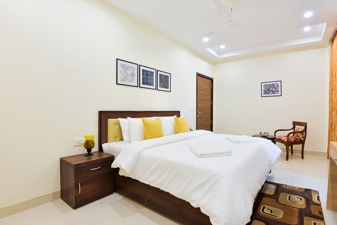 Un dormitorio ordenado con cama, mesita de noche y una silla.