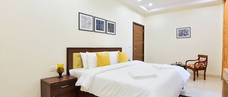 Un dormitorio ordenado con cama, mesita de noche y una silla.