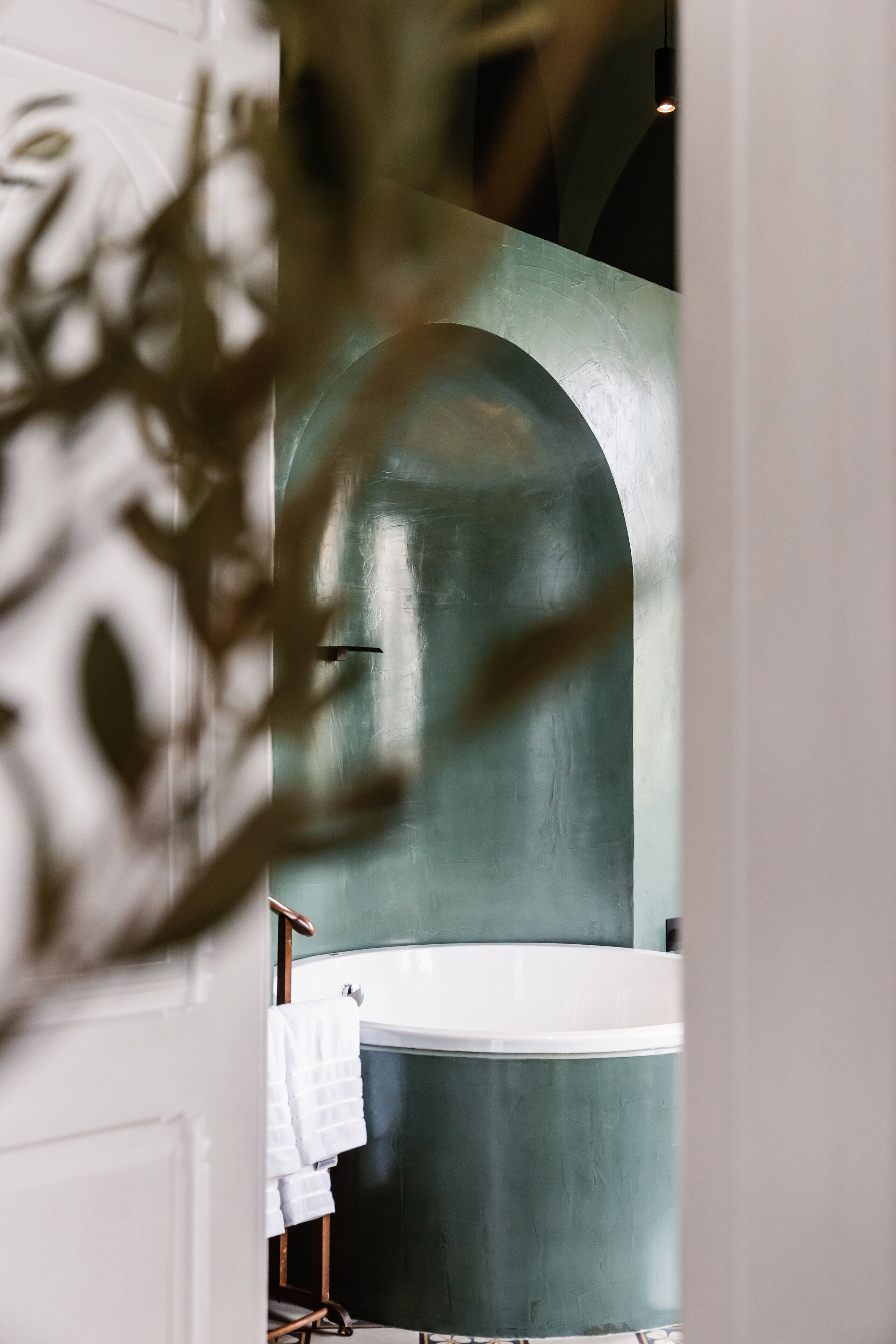A bathroom with a large bathtub, a towel rack, and a door frame.