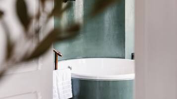 A bathroom with a large bathtub, a towel rack, and a door frame.