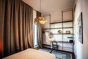A hotel room with a bed, a desk with a chair, a hanging light fixture, and a wardrobe. - Palazzo Piccinno (Parabita)