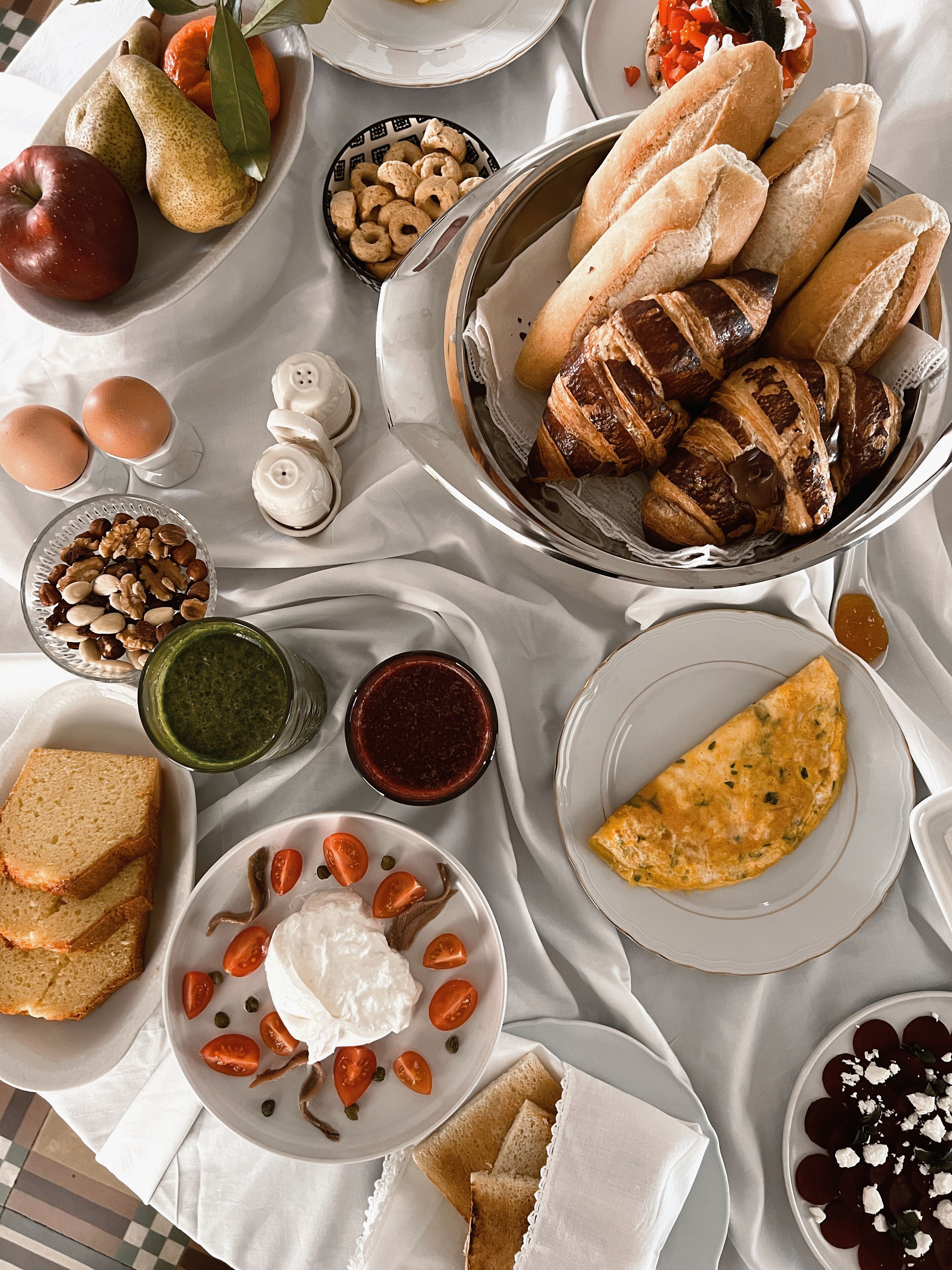 Una mesa con diversos alimentos, entre ellos pan, huevos y frutas.