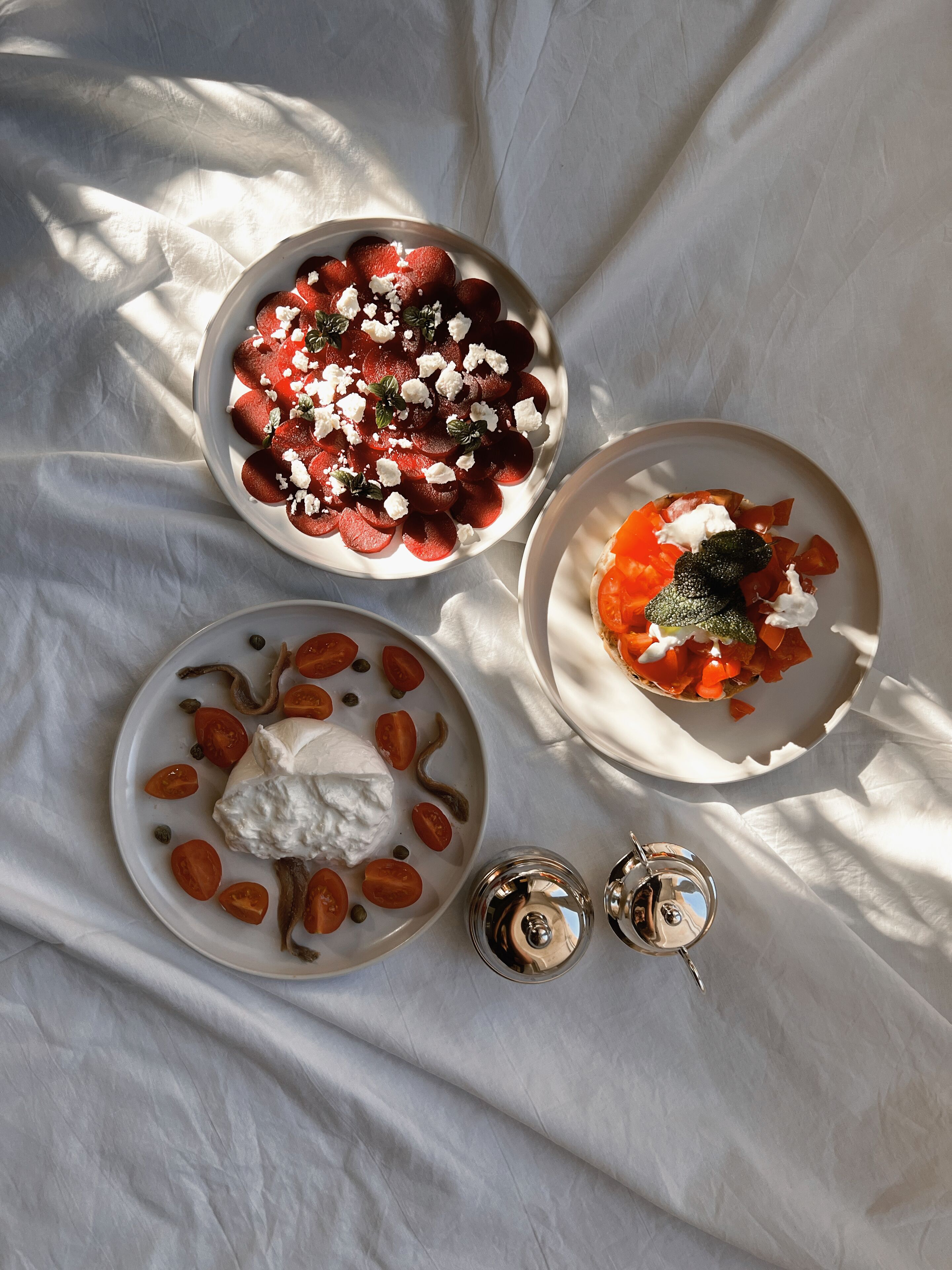 Tres platos de comida sobre un paño blanco.