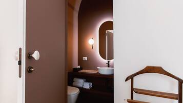 A bathroom with a wooden vanity, a white sink, and a mirror.
