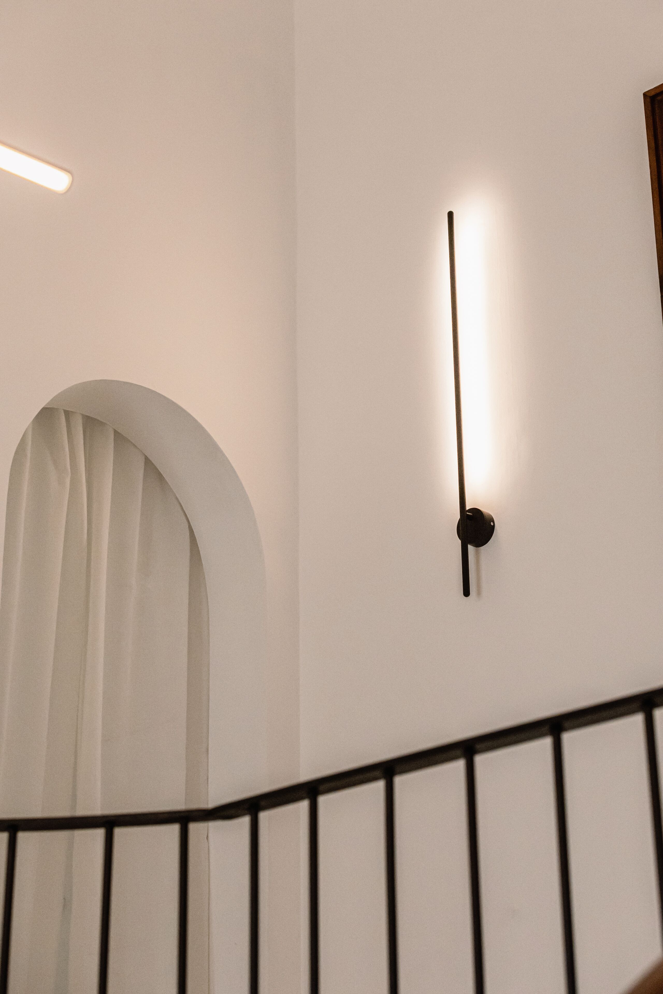 A staircase with a black railing and a wall-mounted light fixture.