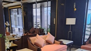 Een moderne zithoek met een bank, fauteuils, een salontafel en een lamp.