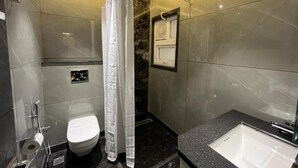 Een moderne badkamer met een douche, toilet en bad.