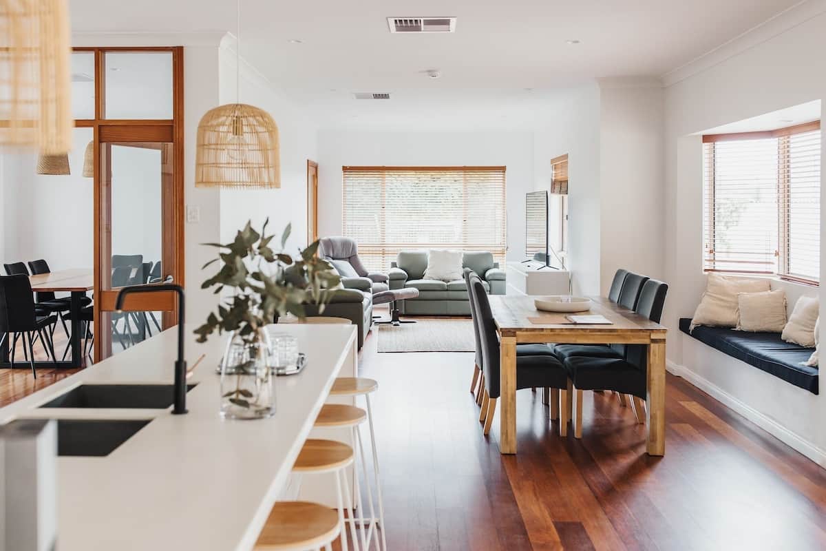 Uma sala de estar moderna com área de jantar, sofá e uma grande janela com persianas.