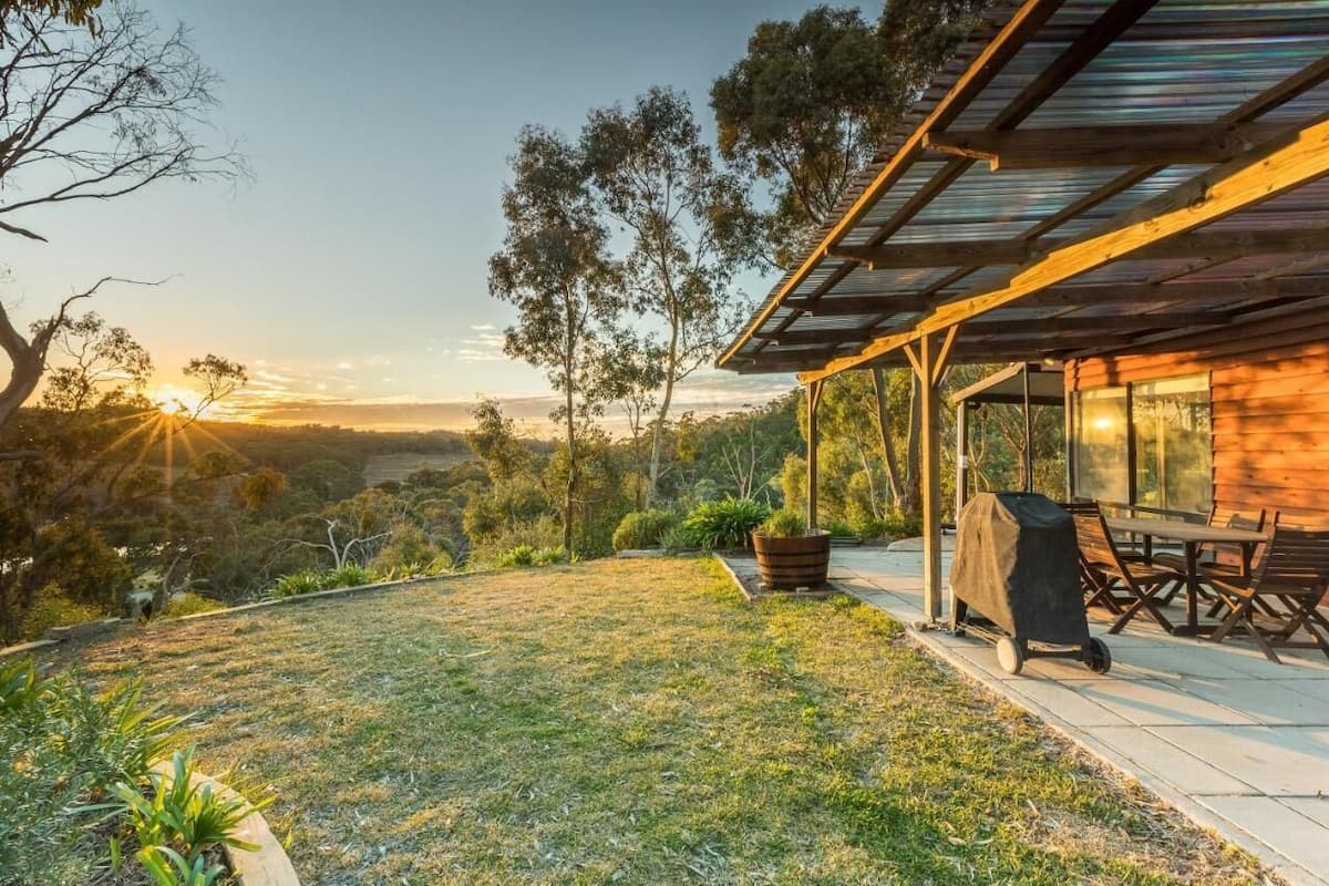 Uma casa moderna com um alpendre coberto, área de churrasco e vista para a paisagem ao redor.