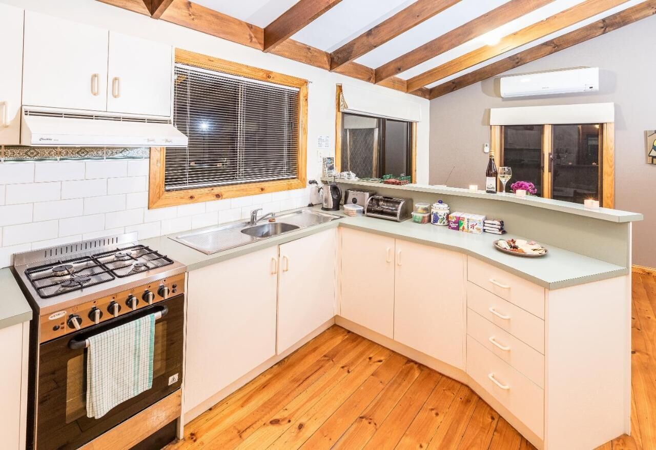A kitchen with white cabinets, a gas stove, a sink, and wooden flooring.