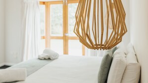 A hotel room with a bed, a hanging light fixture, and a window with curtains. - Skillogalee Estate (Spring Gully)