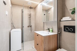 Enjoy a refreshing shower in this modern bathroom featuring a walk-in shower, pedestal sink, and heater.