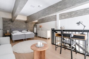 Cozy retreat with a large bed, desk, and round table, featuring a minimalist design with clean lines and neutral tones.