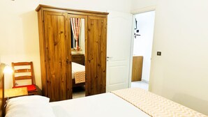 Un dormitorio con cama, armario de madera, una silla y mesita de noche.