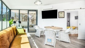 A modern living room with a sofa, wicker chairs, a dining table, and a TV mounted on the wall. - Safari Relaks i Aktywny Wypoczynek Idealna Lokalizacja (Trzebiatow)