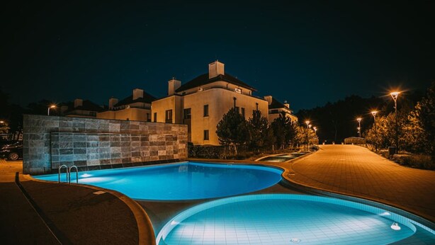 A swimming pool with a stone wall and a building in the background. - Marina Dwupoziomowy Apartament Przy pla y Baltica Heaven (Trzebiatow)