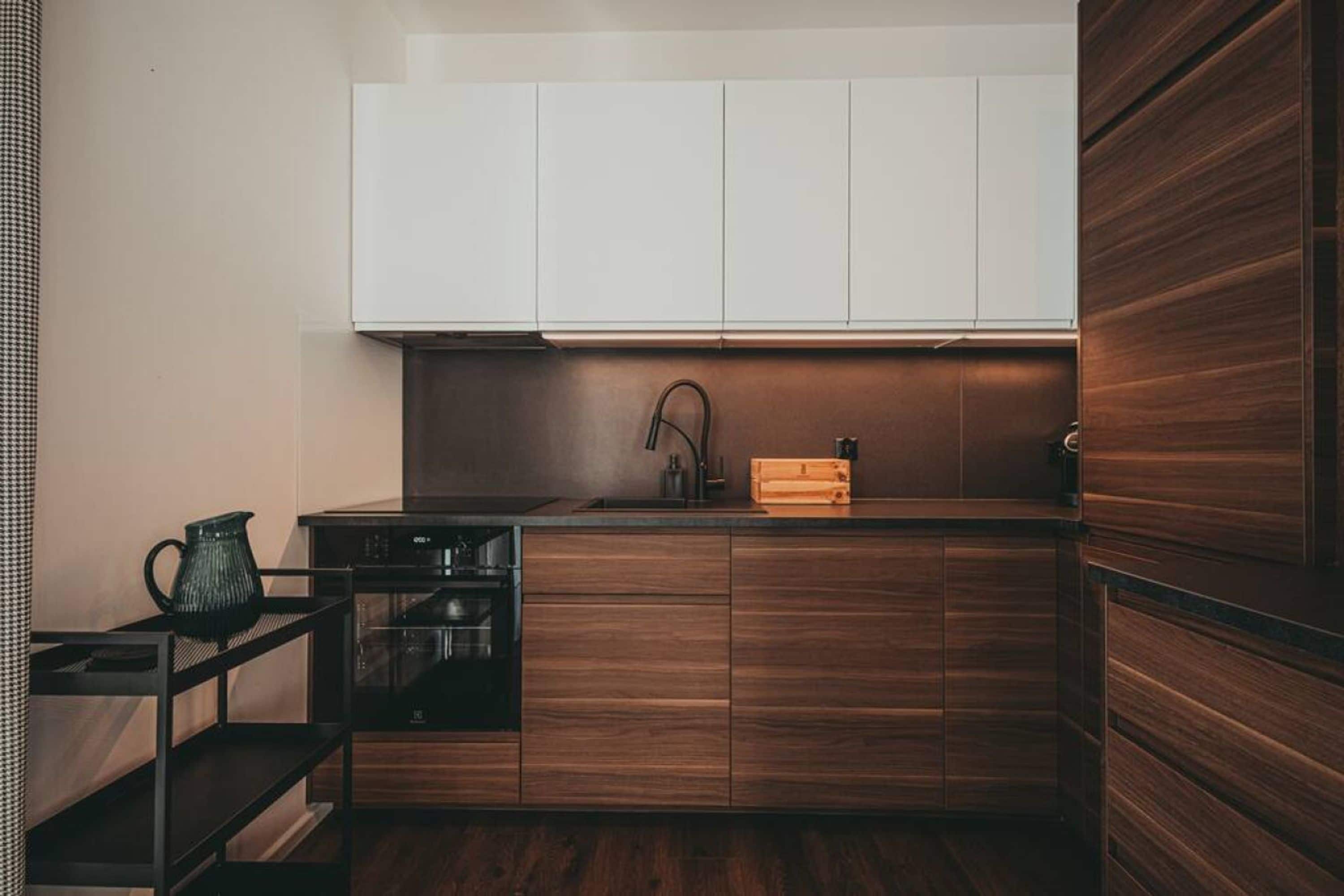 Una cocina moderna con armarios de madera, un lavamanos de acero inoxidable y un horno empotrado.