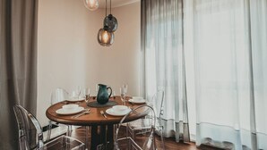 Un comedor con una mesa redonda dispuesta para cuatro personas, sillas transparentes, una jarrón y vasos.