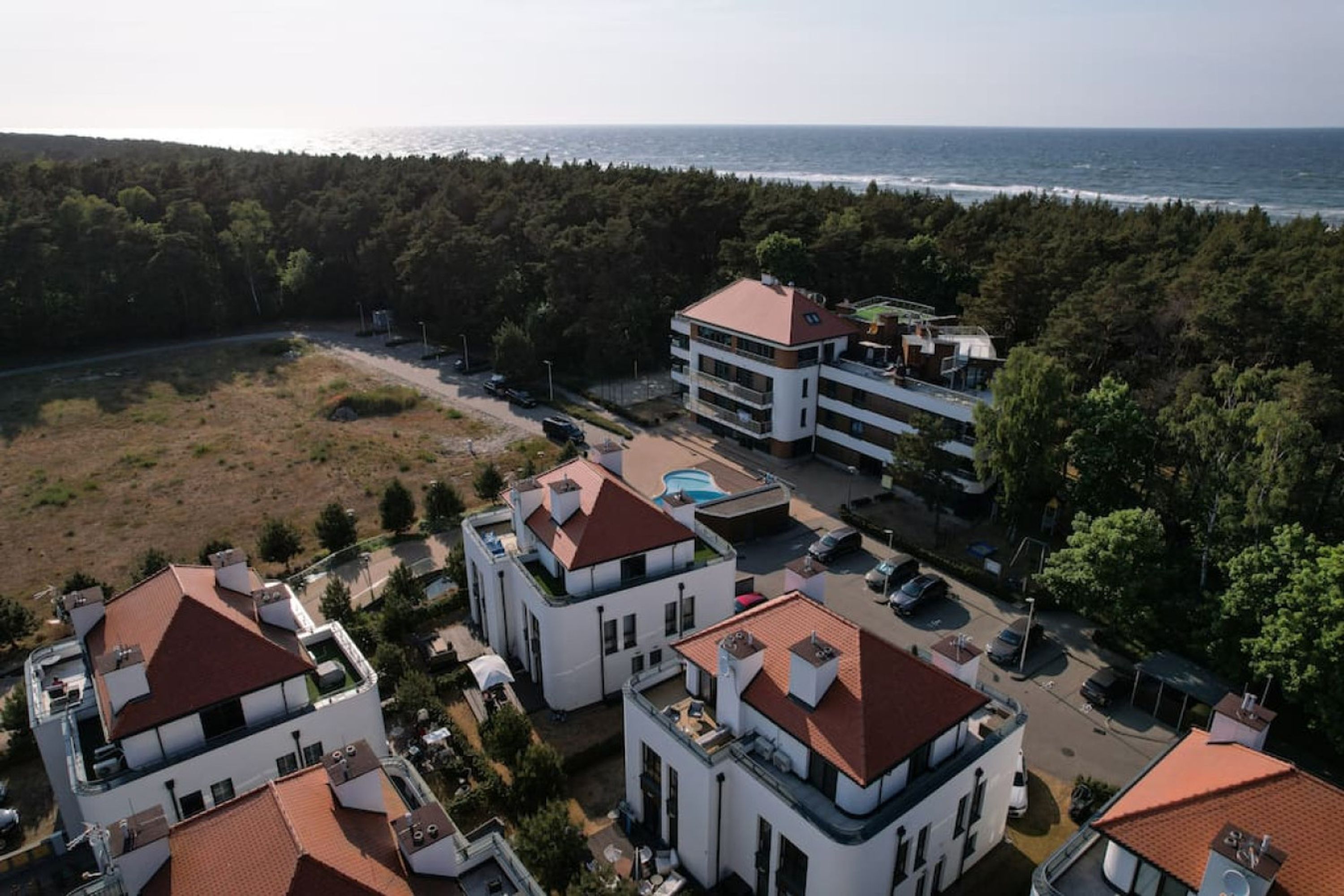 Una zona residencial costera con edificios modernos, una piscina y vista al mar.