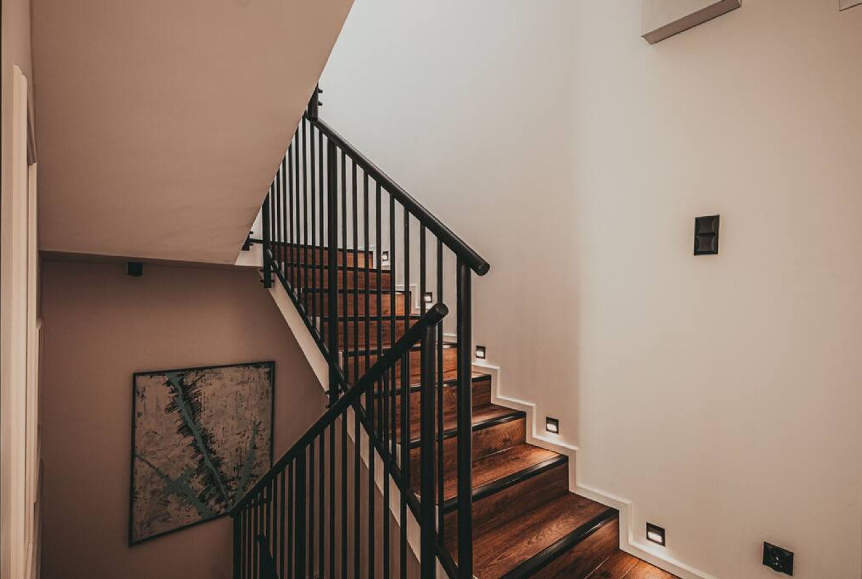 A staircase with wooden steps and black railings, leading to a landing.