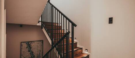 A staircase with wooden steps and black railings, leading to a landing.