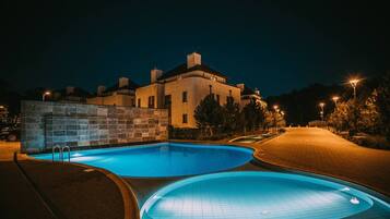 A swimming pool with a stone wall and a building in the background.