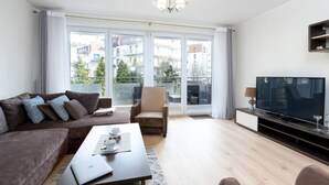 A modern living room with a sofa, armchair, and a flat-screen TV. - Santo Relaks nad Morzem Blisko Centrum i Parku (Kolobrzeg)