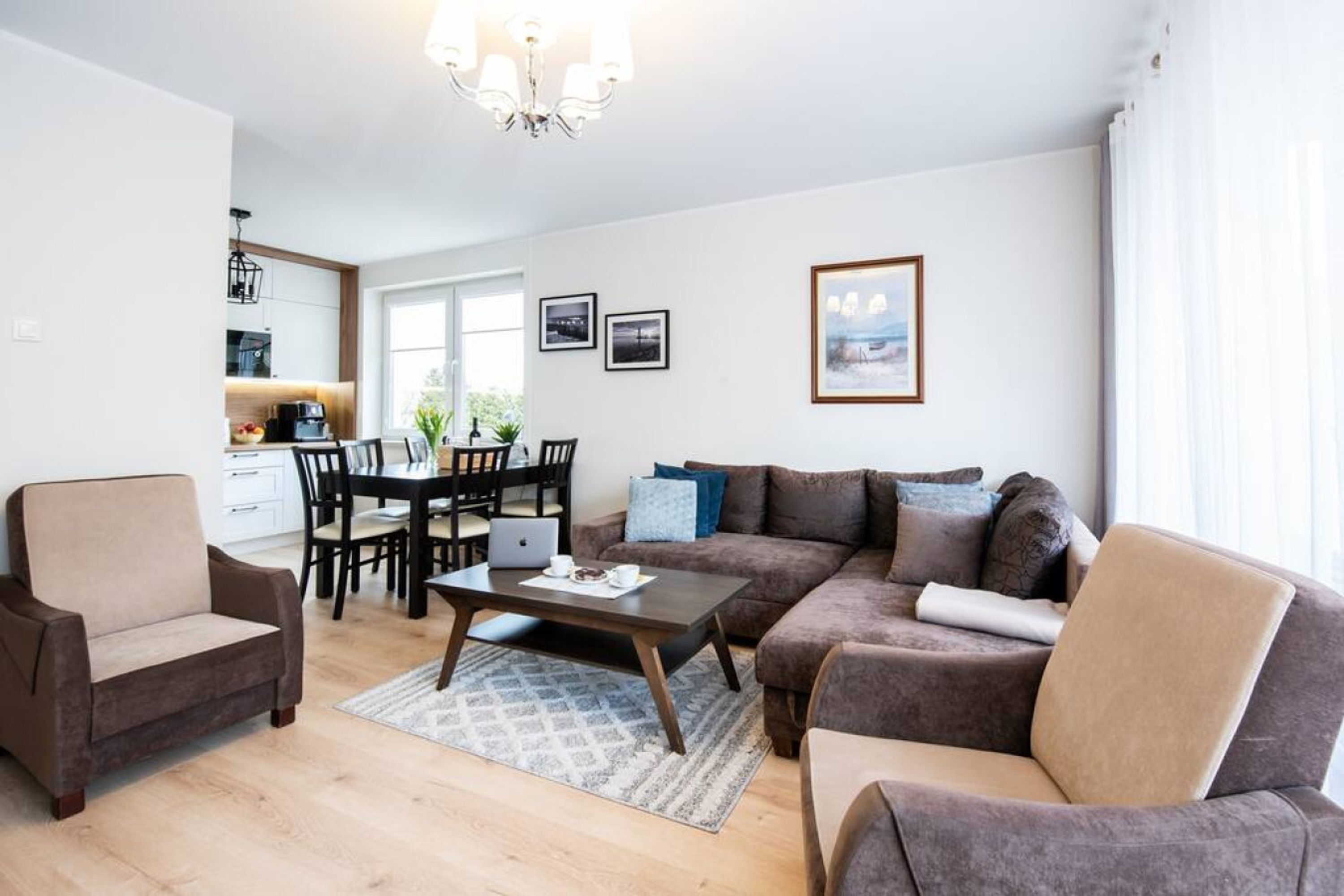 Un salon moderne avec un canapé marron, une table basse et un coin repas comprenant une table et des chaises.