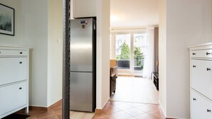 A modern kitchen with a built-in refrigerator, a dining area with a table and chairs, and a view of a balcony with outdoor furniture. - Santo Relaks nad Morzem Blisko Centrum i Parku (Kolobrzeg)