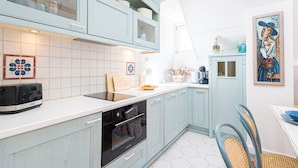 Eine Küche mit hellblauen Schränken, einem Toaster, einer Spüle und einem Bild an der Wand.