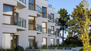 A modern multi-story building with balconies, large windows, and a landscaped garden area. - Hermoso Wypoczynek w Strefie SPA Blisko Morza (Mielno)