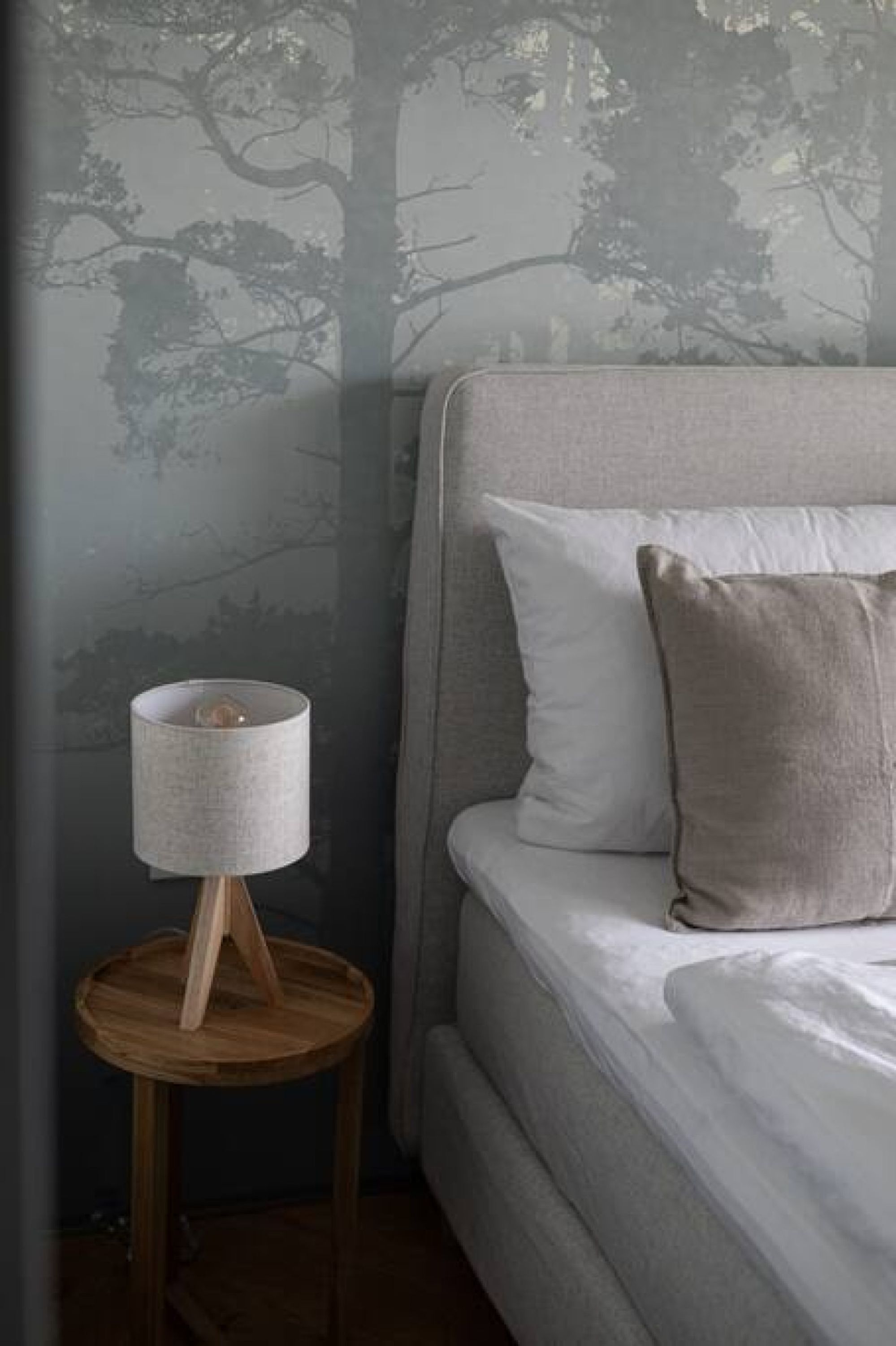 A bedroom with a bed, a nightstand, and a lamp.