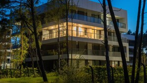 A multi-story building with large windows and balconies, surrounded by trees. - Natural Rogowo Rodzinny Pla a i Natura (Trzebiatow)