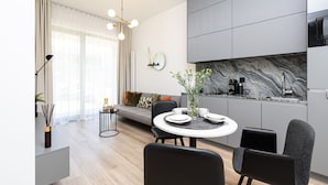 Une cuisine moderne avec un revêtement mural en marbre, un coin repas doté d’une table ronde et un canapé dans l’espace salon.