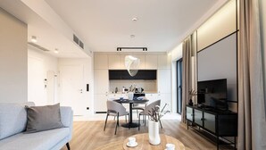 A modern living room with a sofa, a dining table, and a kitchen area in the background. - Sunrise Tw j Prywatny Widok na Ba tyk (Trzebiatow)